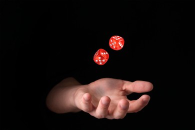 Image of Man throwing red dice in darkness, closeup