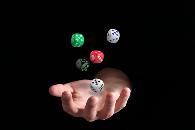 Image of Man throwing different dice in darkness, closeup