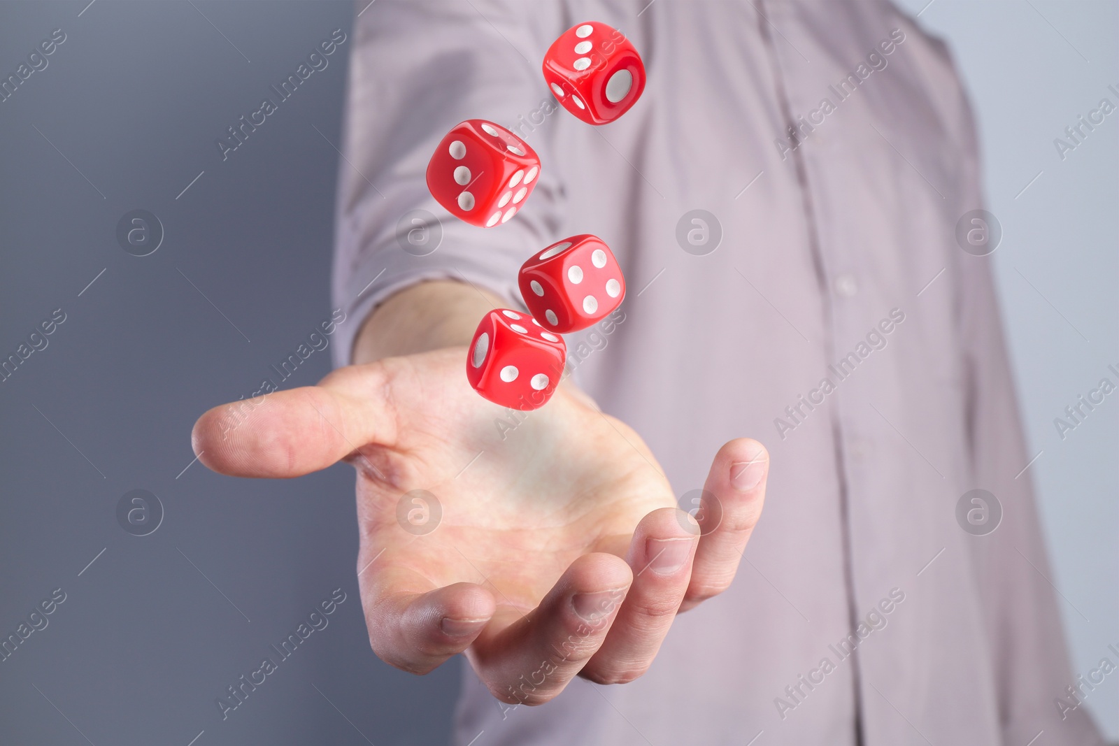 Image of Man throwing red dice on grey background, closeup