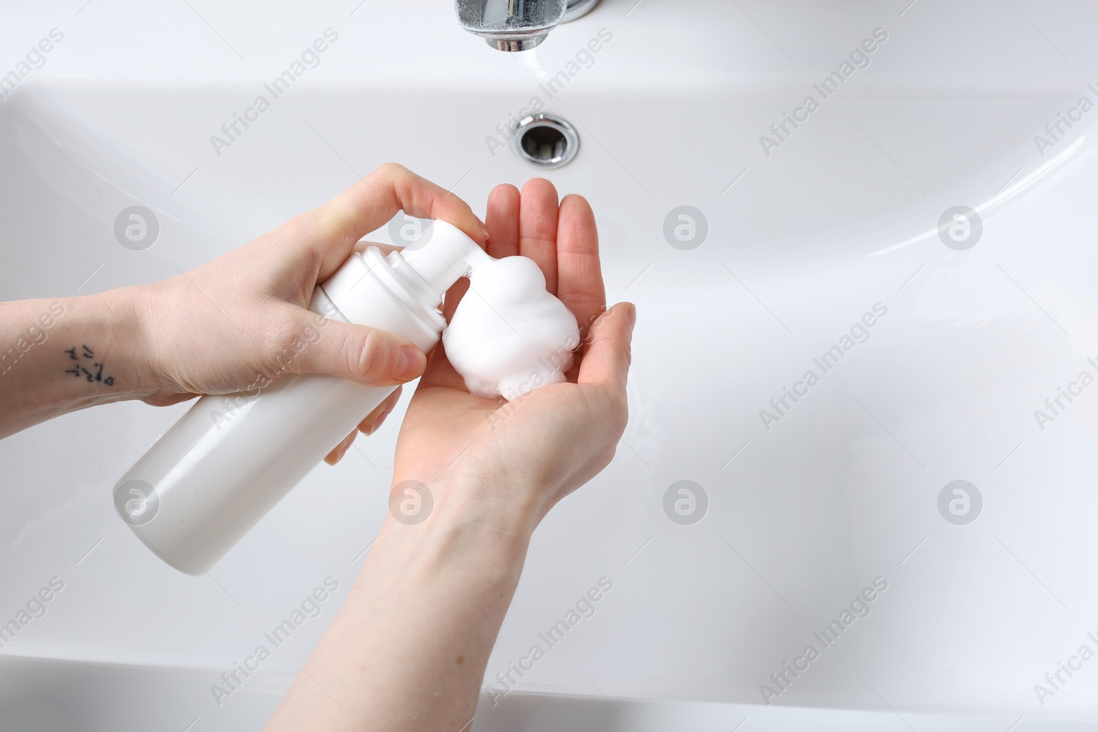 Photo of Woman washing hands with cleansing foam near sink in bathroom, closeup