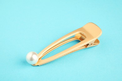 Photo of Beautiful bijouterie. Elegant hair clip on light blue background, closeup