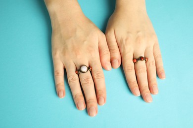 Photo of Beautiful bijouterie. Woman wearing stylish rings on light blue background, top view