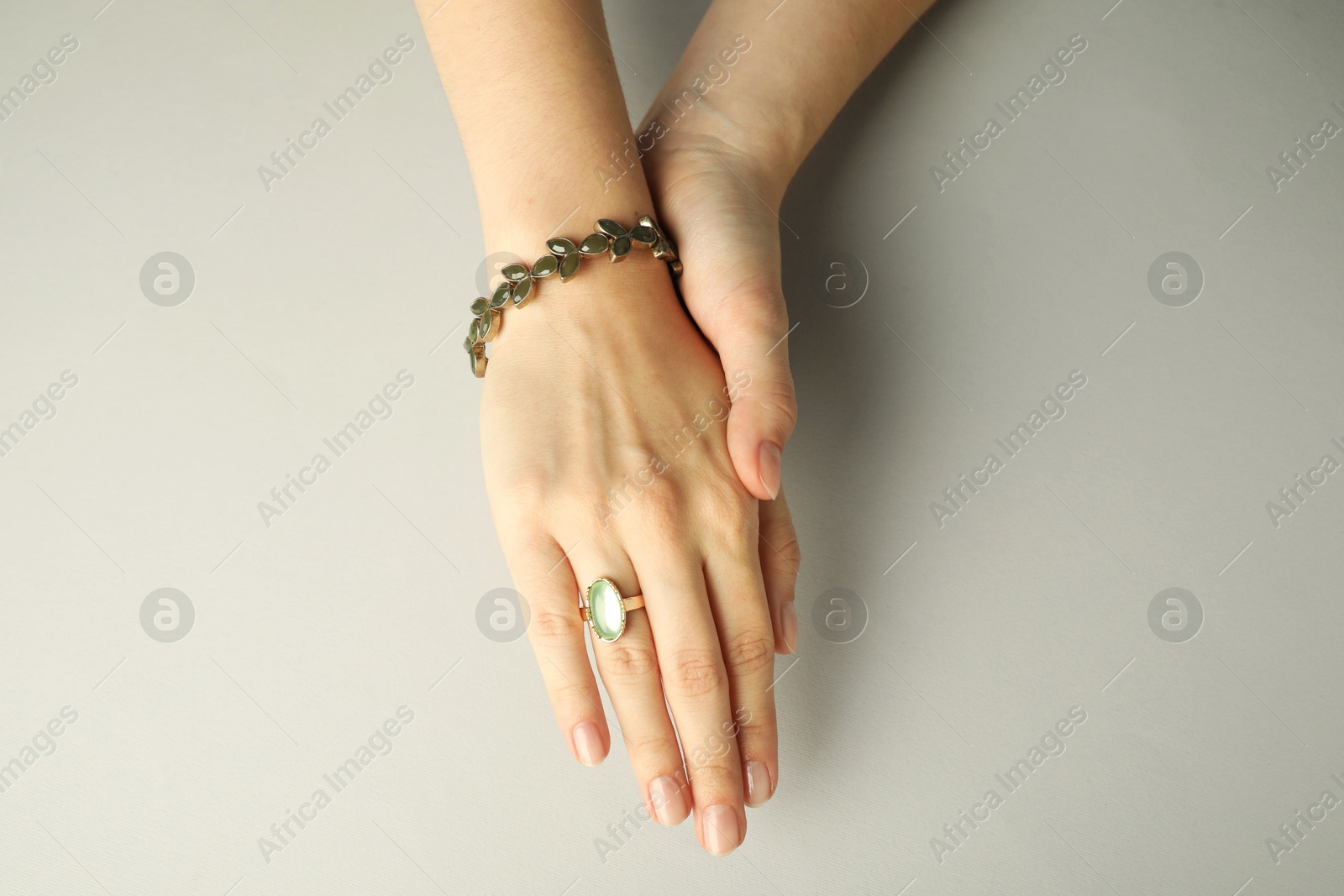 Photo of Beautiful bijouterie. Woman wearing stylish ring and bracelet on light grey background, top view