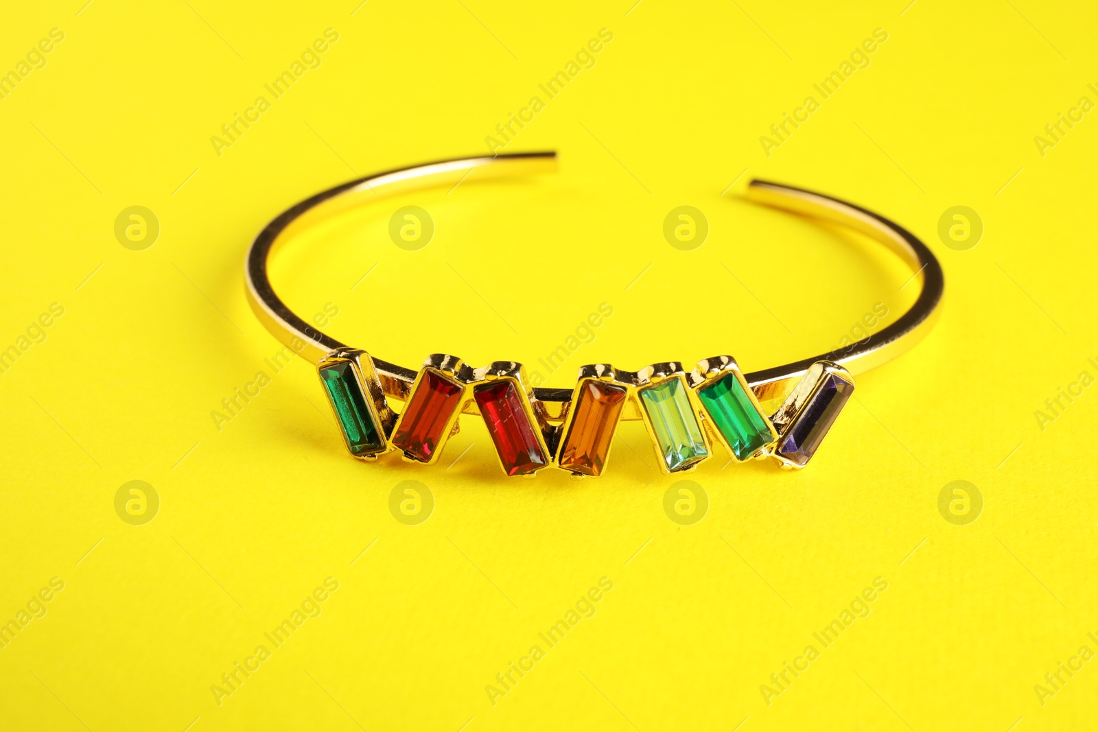 Photo of Beautiful bijouterie. Stylish bracelet on yellow background, closeup