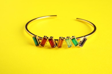 Photo of Beautiful bijouterie. Stylish bracelet on yellow background, closeup