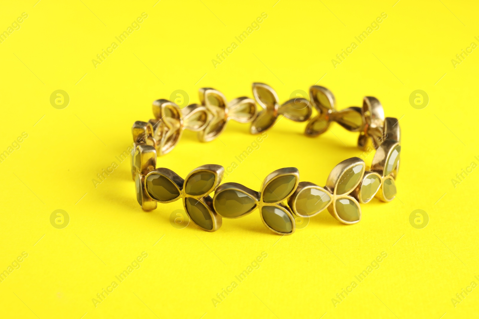 Photo of Beautiful bijouterie. Stylish bracelet on yellow background, closeup