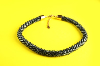 Photo of Beautiful bijouterie. Stylish bracelet on yellow background, closeup