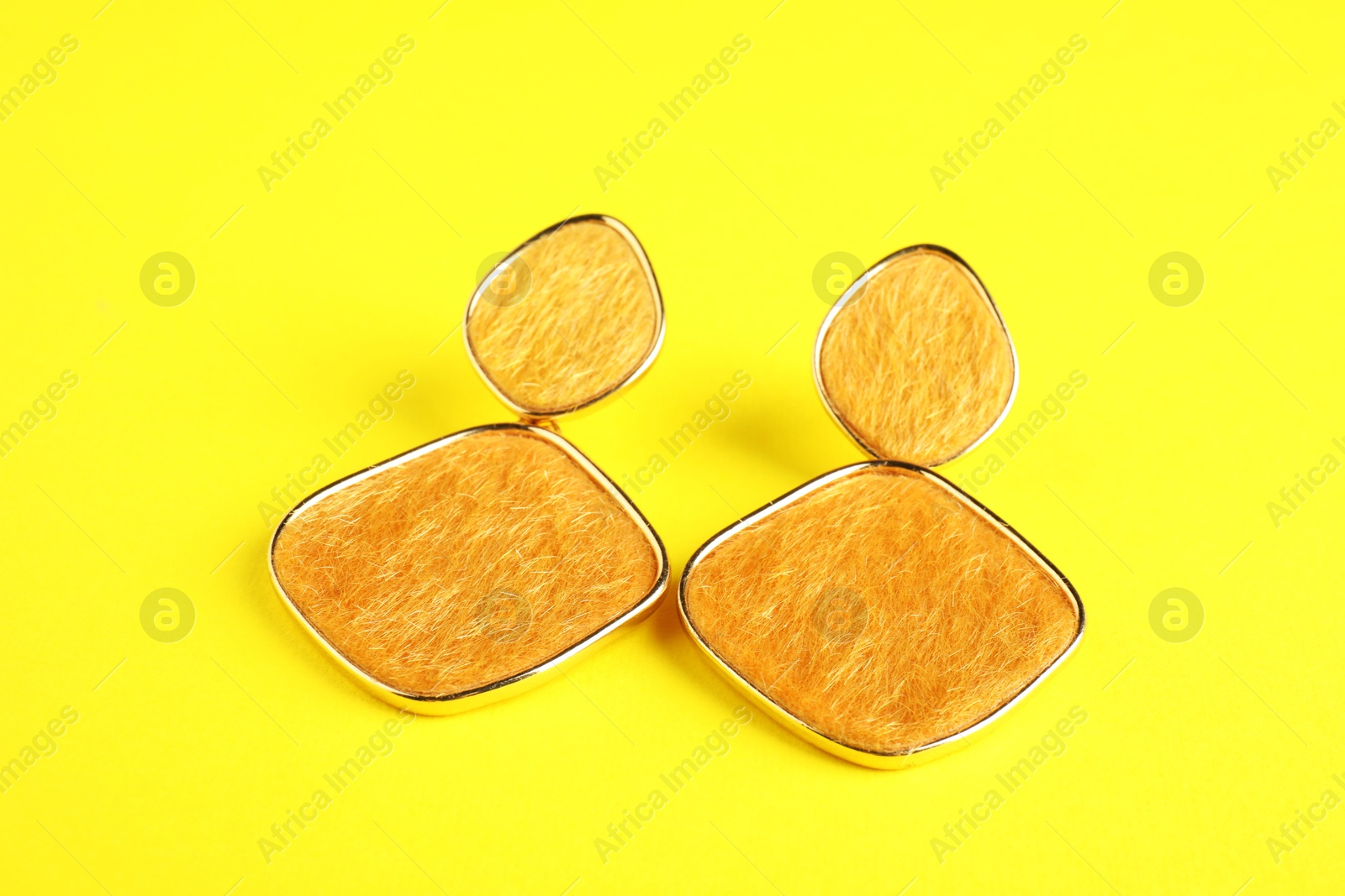 Photo of Beautiful bijouterie. Stylish earrings on yellow background