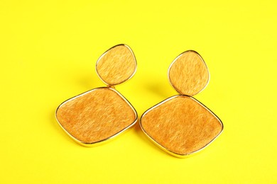 Photo of Beautiful bijouterie. Stylish earrings on yellow background