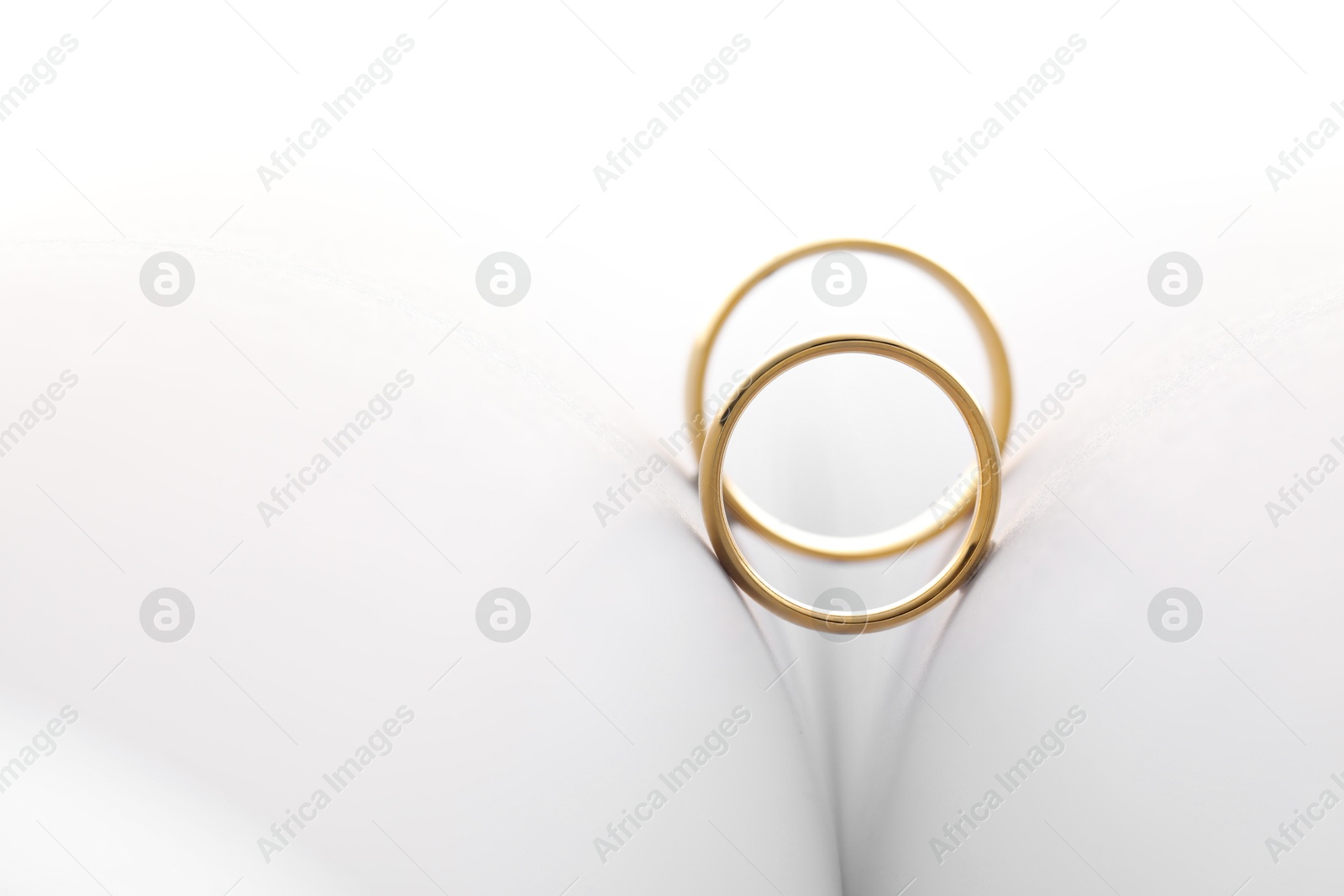 Photo of Beautiful golden wedding rings on light background, space for text