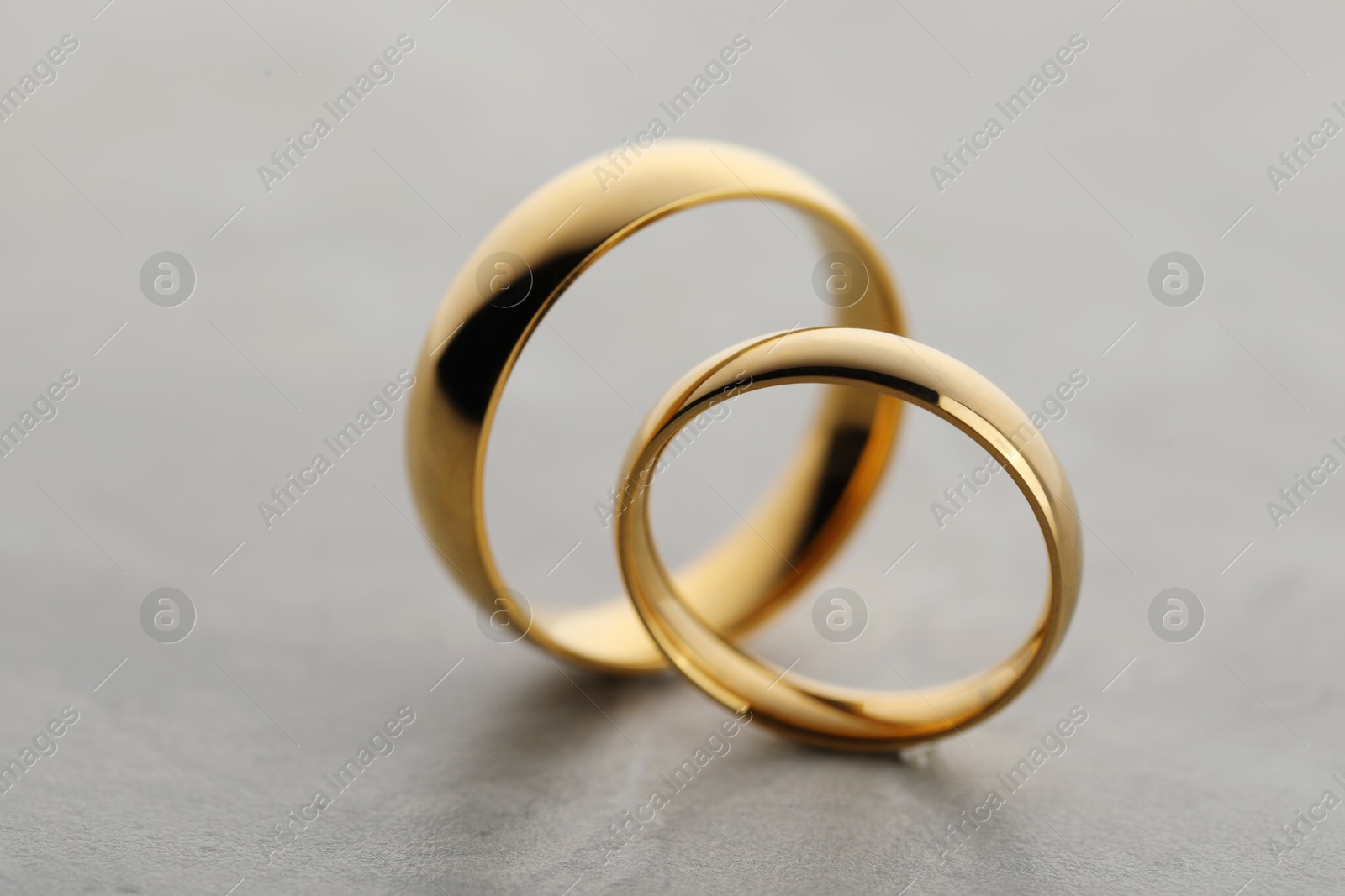 Photo of Beautiful golden wedding rings on gray background, closeup