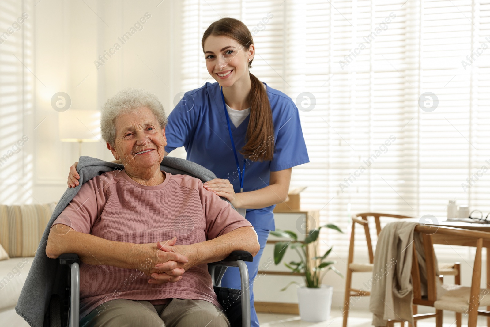 Photo of Caregiver covering senior woman with blanket indoors. Home health care service