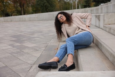 Photo of Woman with injured back on stairs outdoors after fall. Dangerous accident