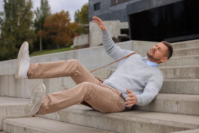 Photo of Man falling on stairs outdoors. Dangerous accident