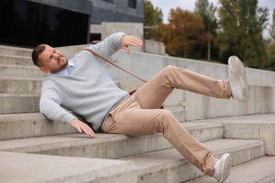 Photo of Man falling on stairs outdoors. Dangerous accident