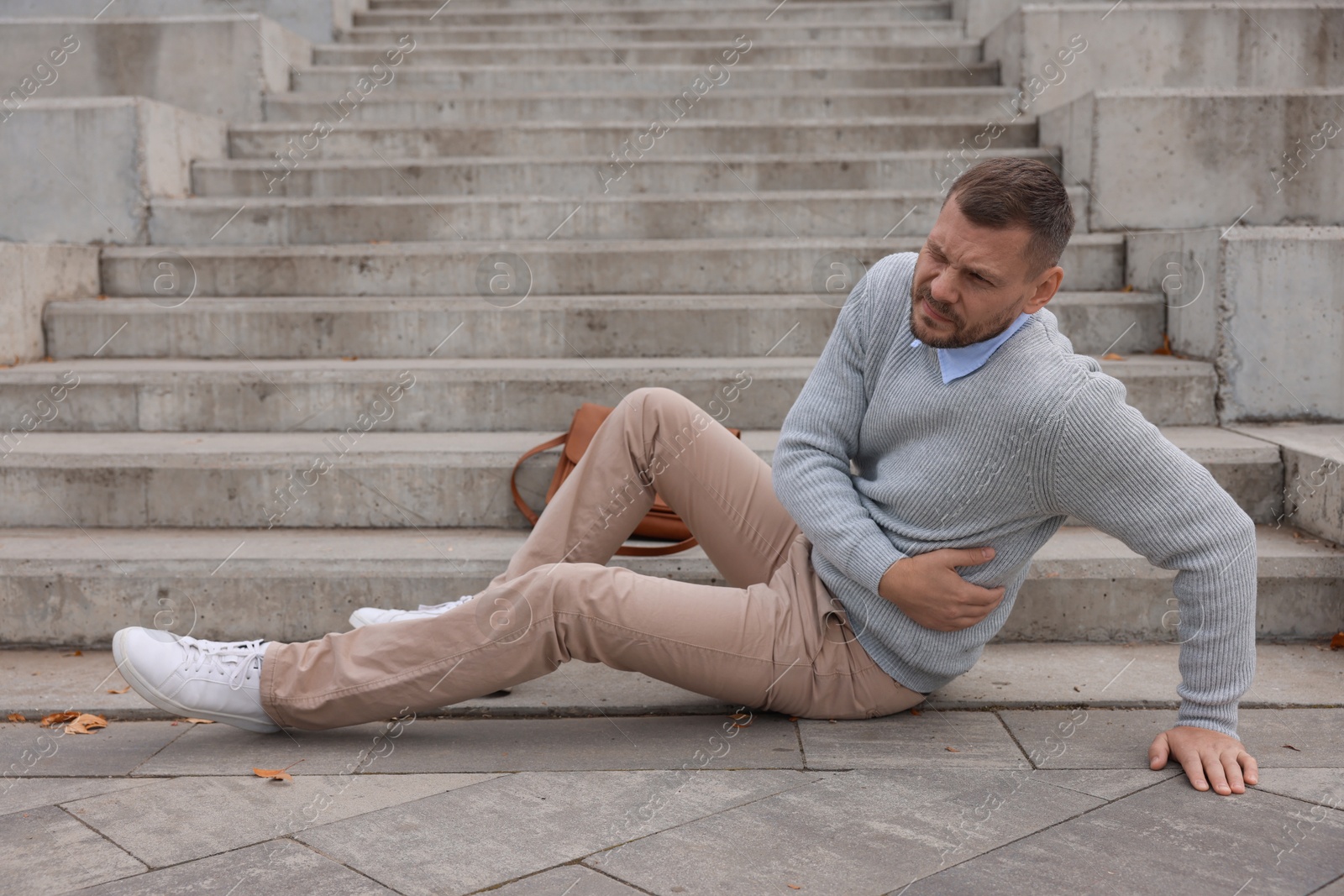 Photo of Injured man on stairs outdoors after fall. Dangerous accident