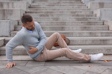 Photo of Injured man on stairs outdoors after fall. Dangerous accident