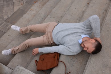 Photo of Man with injured head on stairs outdoors after fall. Dangerous accident