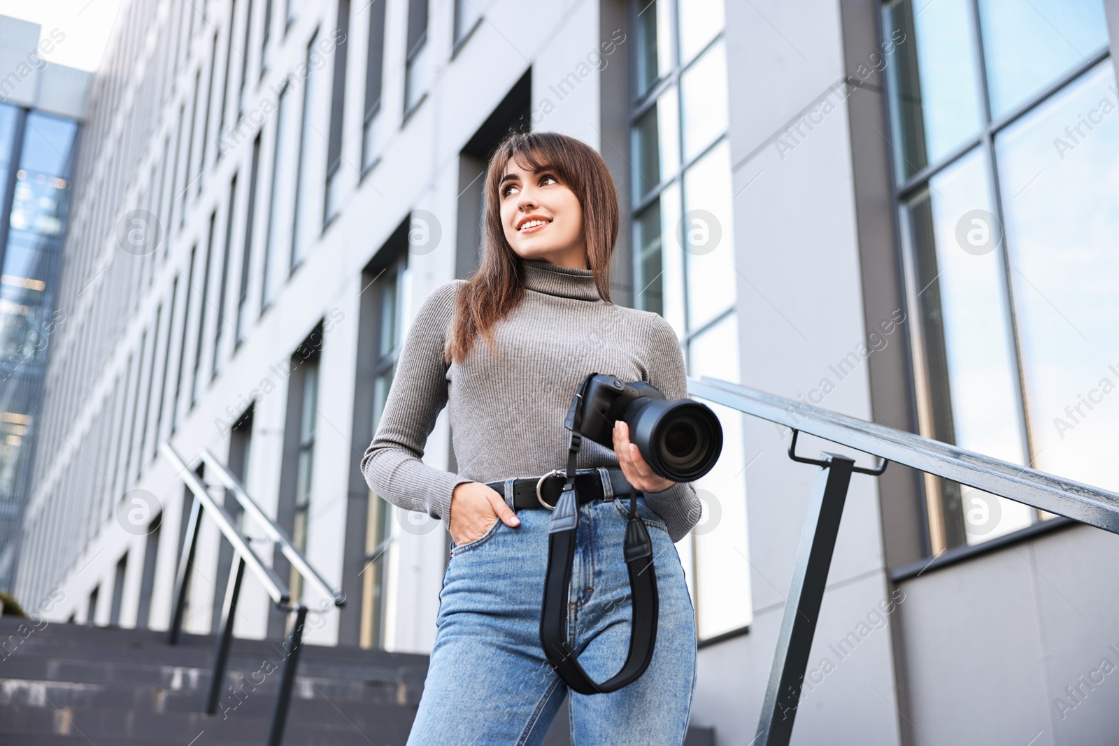 Photo of Professional photographer with digital camera outdoors, low angle view