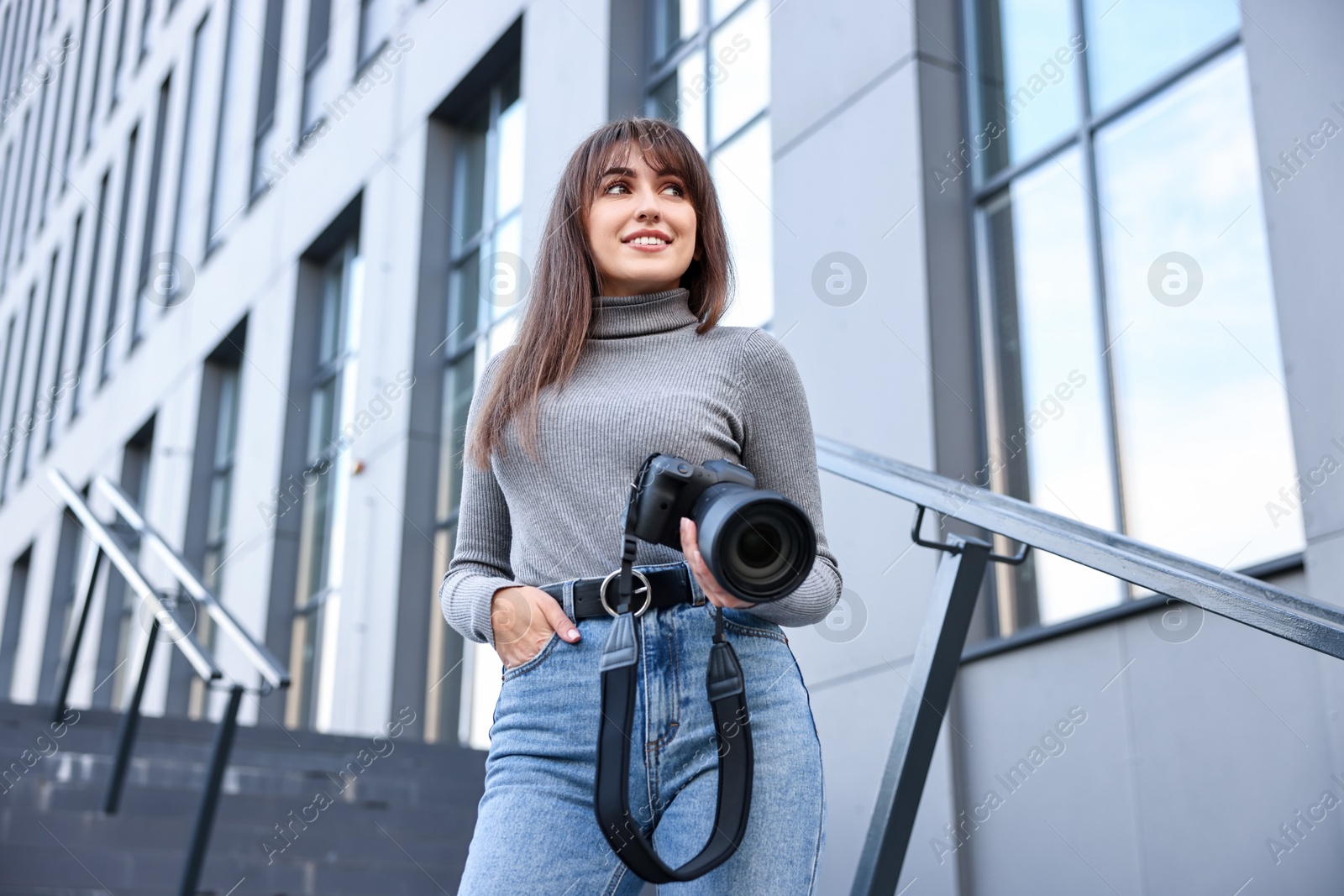 Photo of Professional photographer with digital camera outdoors, low angle view