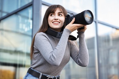 Photo of Professional photographer with digital camera near building outdoors, low angle view