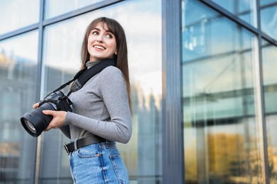 Photo of Professional photographer with digital camera outdoors, low angle view. Space for text