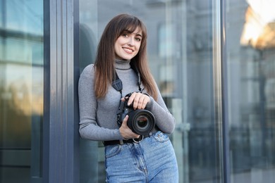 Professional photographer with digital camera near building outdoors