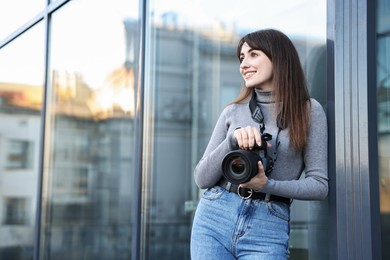 Professional photographer with digital camera near building outdoors. Space for text