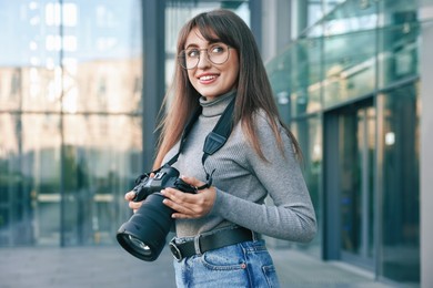 Professional photographer with digital camera near building outdoors