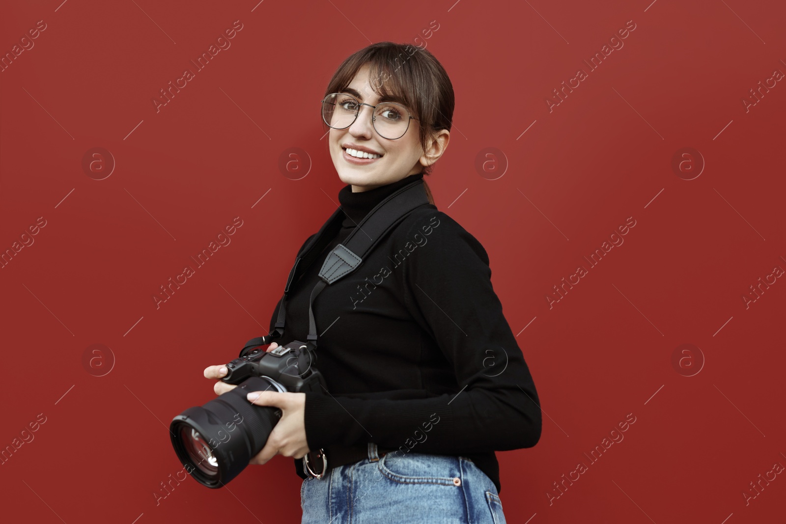 Photo of Professional photographer with digital camera near red wall outdoors