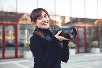 Photo of Professional photographer with digital camera near building outdoors