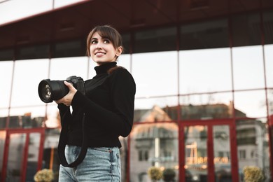 Photo of Professional photographer with digital camera near building outdoors. Space for text