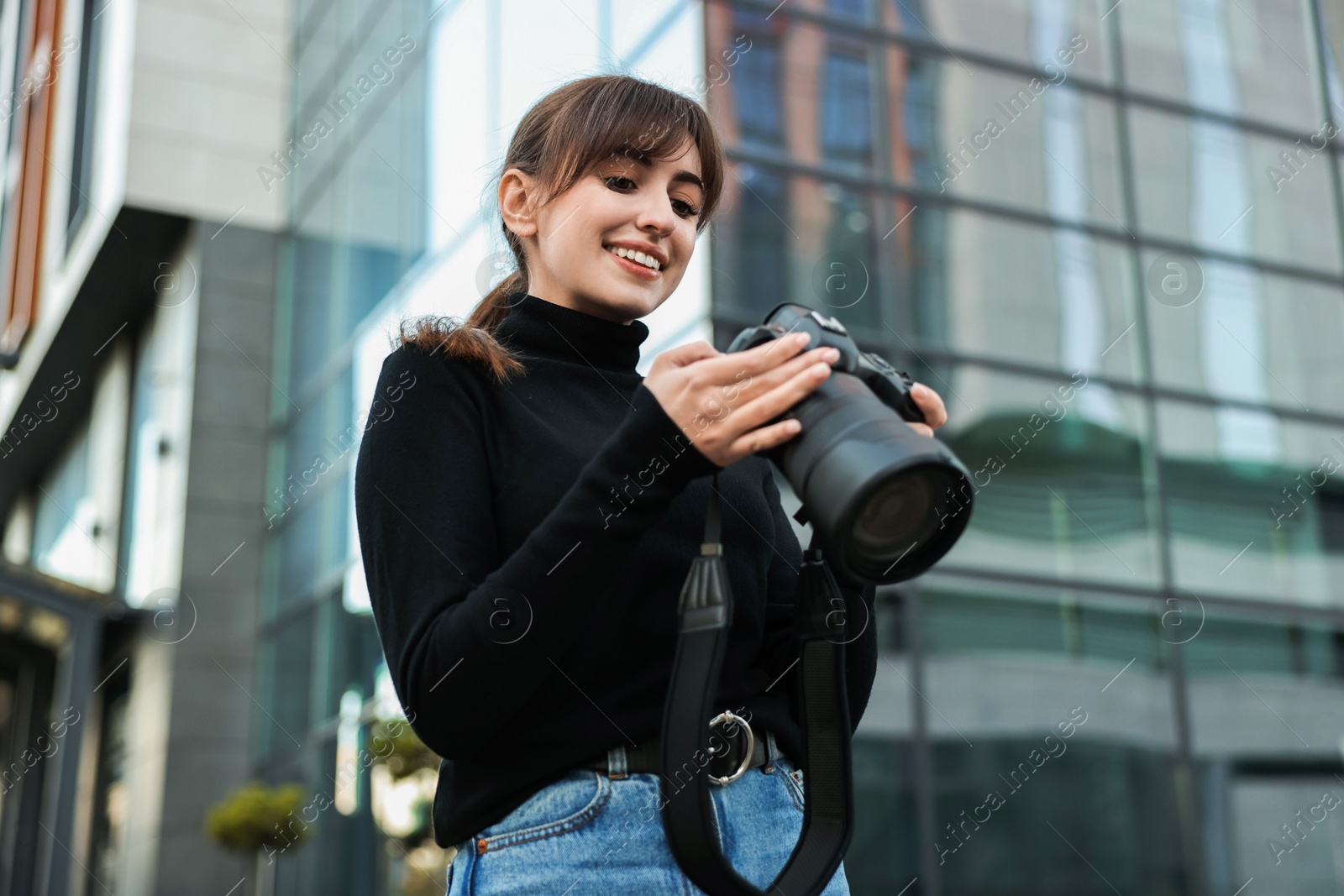 Photo of Professional photographer with digital camera outdoors, low angle view