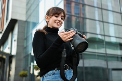 Photo of Professional photographer with digital camera outdoors, low angle view