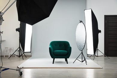 Professional lighting equipment setup and armchair in modern photo studio