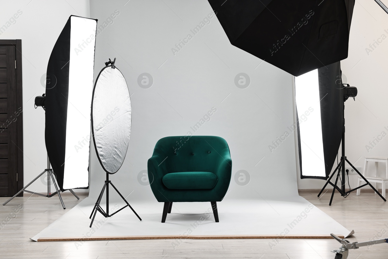 Photo of Professional lighting equipment setup and armchair in modern photo studio