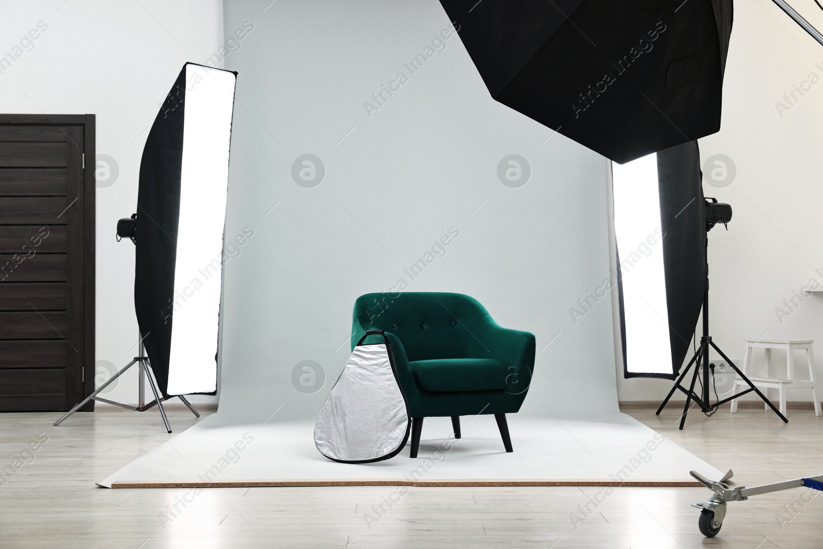 Photo of Professional lighting equipment setup and armchair in modern photo studio