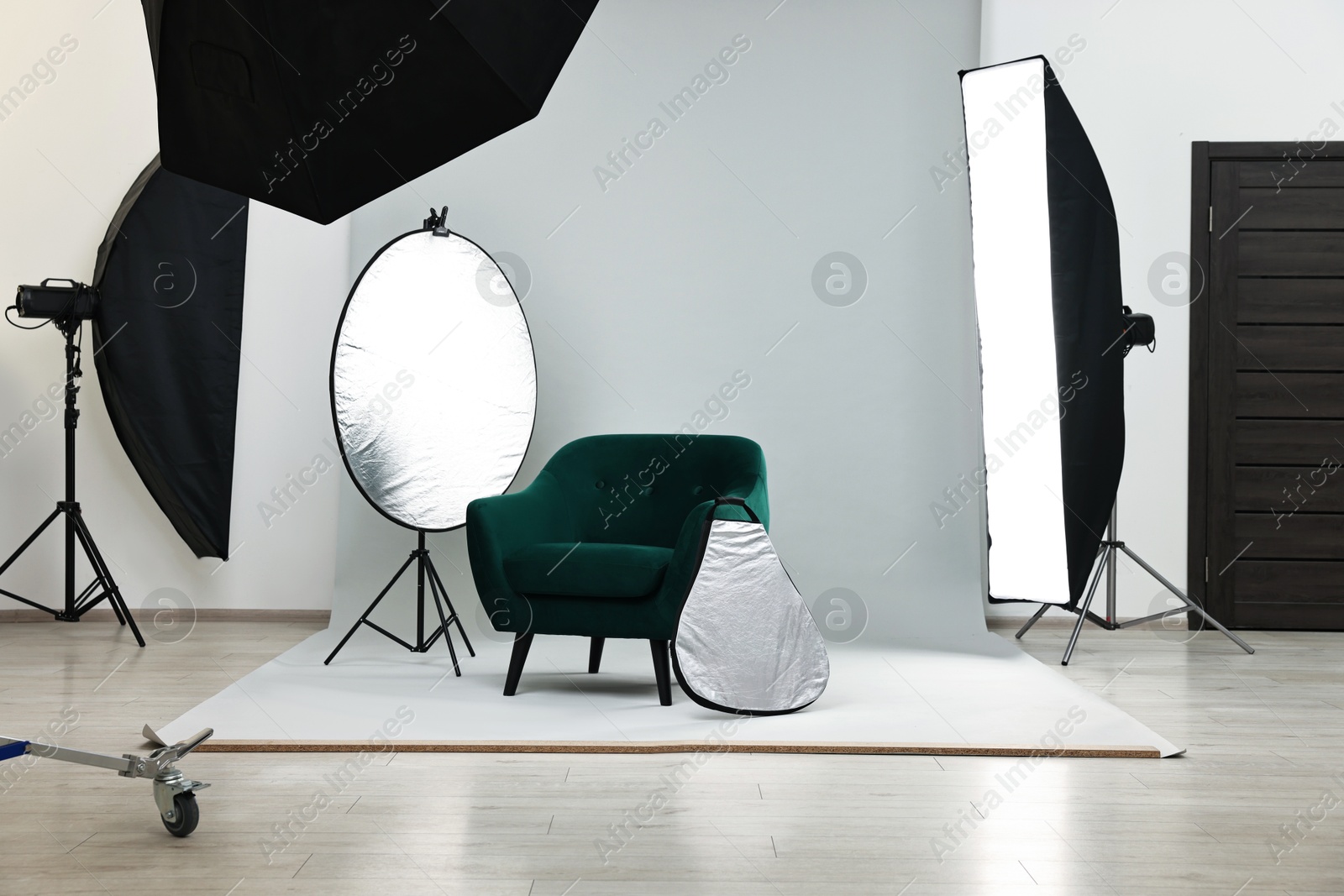 Photo of Professional lighting equipment setup and armchair in modern photo studio