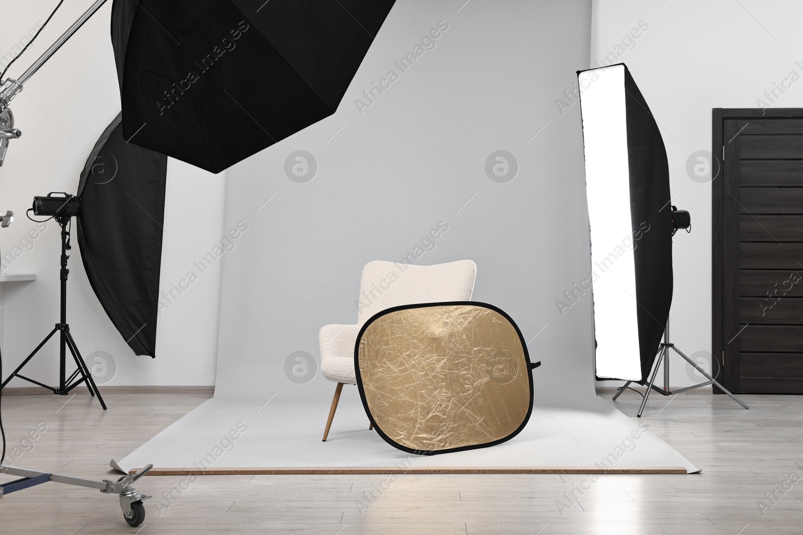 Photo of Professional lighting equipment setup and armchair in modern photo studio