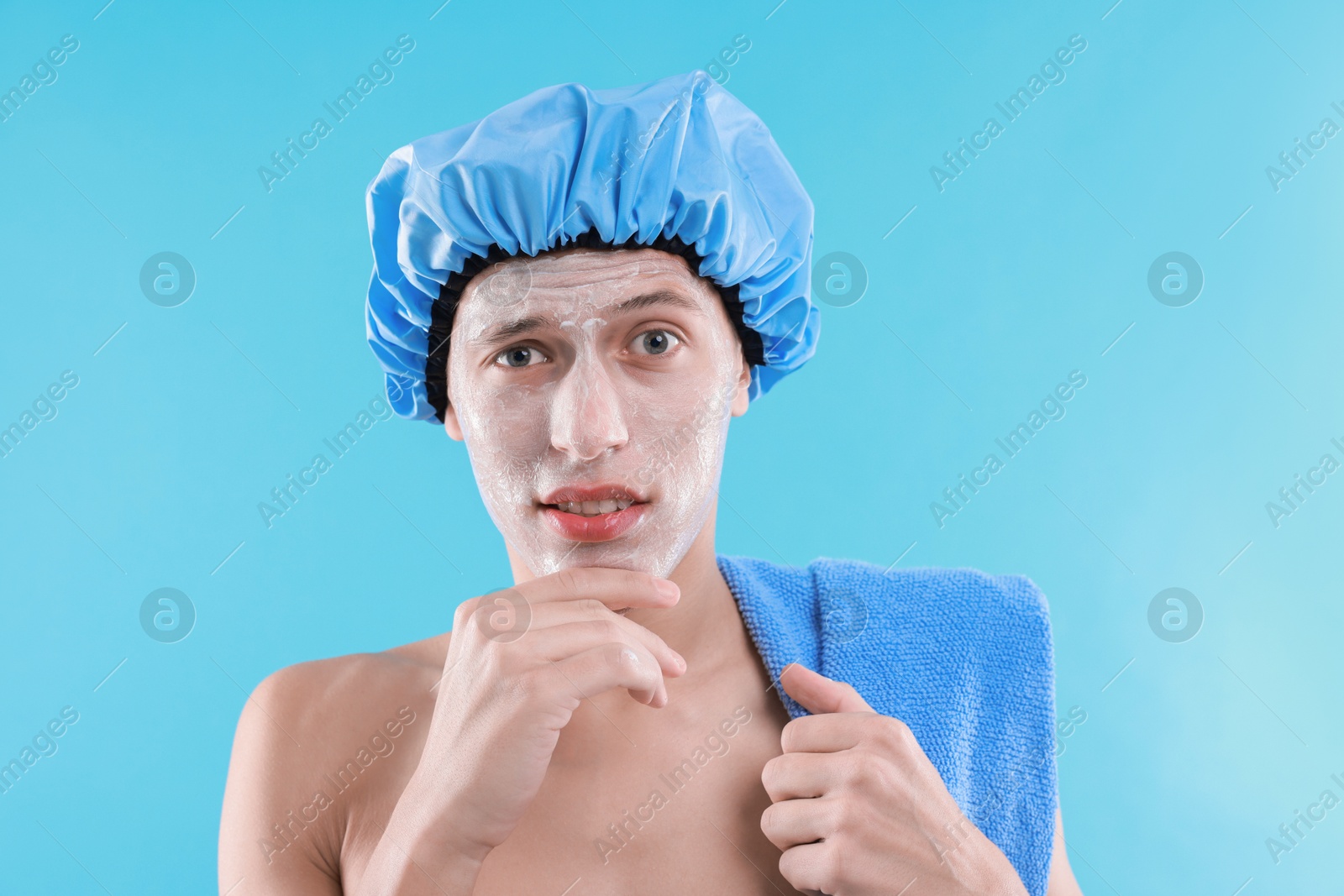 Photo of Man in shower cap with cream on his face against light blue background