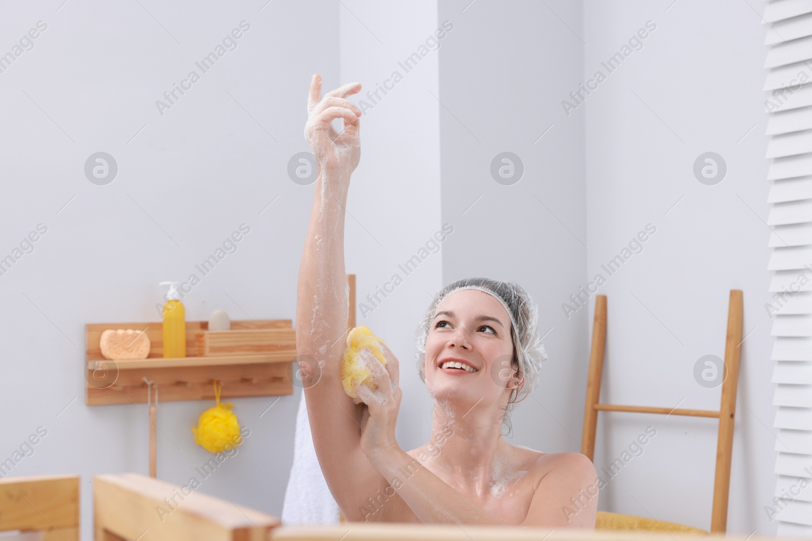 Photo of Woman with cap and mesh sponge taking shower in bathroom