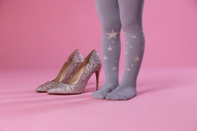 Photo of Child wearing tights and heels on pink background, closeup