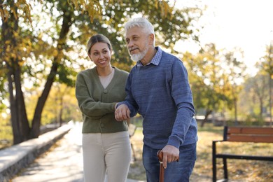 Photo of Caregiver assisting senior man in park. Home health care service