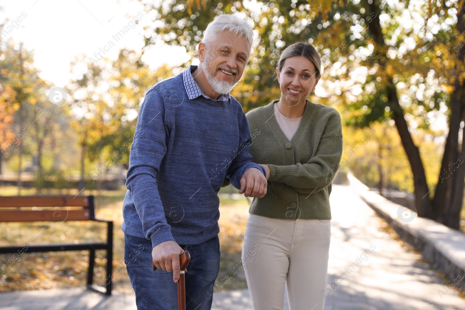 Photo of Caregiver assisting senior man in park. Home health care service