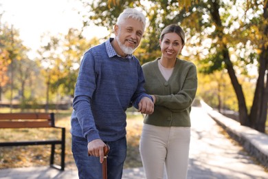 Photo of Caregiver assisting senior man in park. Home health care service