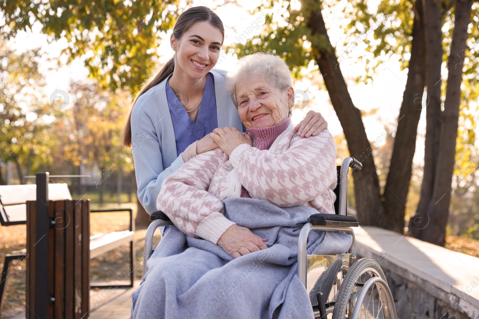 Photo of Caregiver with elderly woman in wheelchair at park