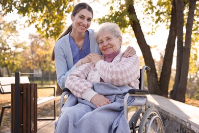 Caregiver with elderly woman in wheelchair at park