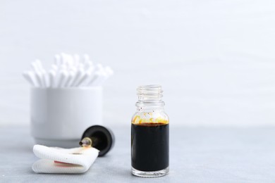 Photo of Bottle of iodine with dropper, piece of bandage and cotton swabs on grey table. Space for text