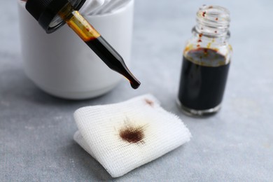 Photo of Dripping iodine on piece of bandage at grey table, closeup