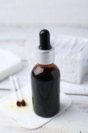 Photo of Bottle of iodine with dropper, cotton pads and swabs on white wooden table, closeup